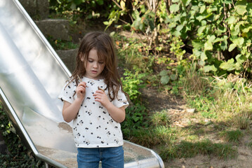 Portrait of a beautiful little girl playing on a slide in the park