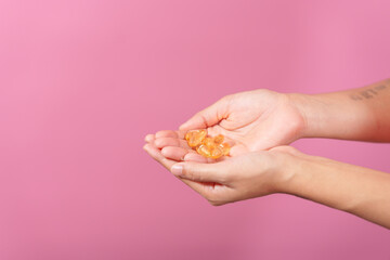 A professional image showcasing a female hand delicately holding a bottle of cod liver oil with her...