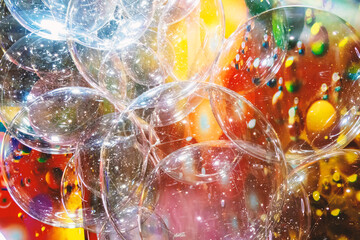 A large number of transparent plastic bubbles floating in the air. The balls are in a colorful...