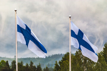 Flag of Finland with dramatic beautiful storm sky with dark clouds and misty background. Interesting composition of two Finnish political emblens. 