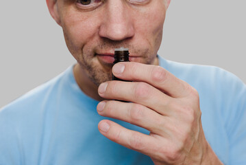 Young man having long-term covid effect and trying to sense smell of essential oil. Scent...