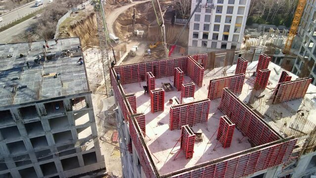 Aerial photography from a drone of a construction site for the construction of a multi-storey building, the process of pouring concrete. Construction of load-bearing walls.