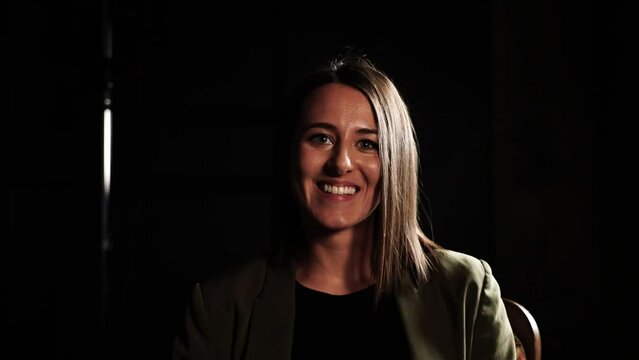 Talking head shot of female during studio type interview in dark environment