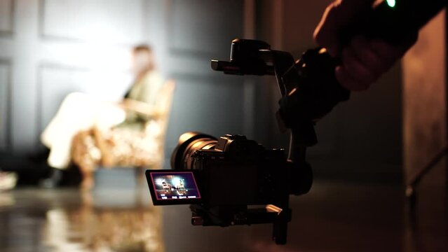 Filmmaker with camera on gimbal approach people during interview in studio