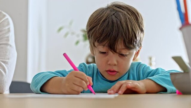 Little Boy Practices Cursive Writing By Tracing On Sample Sheet