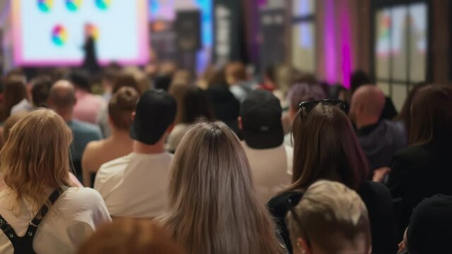 Young audience at a creative self-growth seminar, speaker with presentation out of focus. A gathering for personal creative development. Use in contexts of artistic self-improvement and training