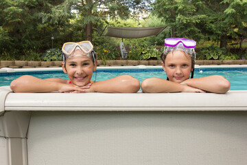 Two young girls are wearing goggles and smiling at the camera