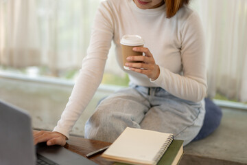 Close-up view of a woman's hands holding a coffee cup and a book, signifying multitasking during a...