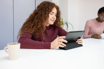 Woman using tablet with colleague in background