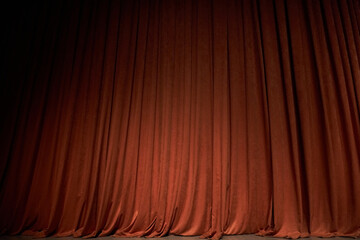 Orange closed curtain or drapes in theater with copy space. Theatrical performance concept. Spot of light on the curtain. 