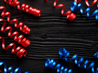 red and blue ribbon for celebration on a black wooden background - 774040009