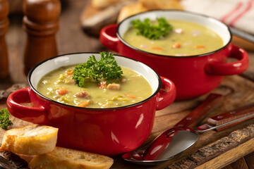 Bowls of split pea soup with ham and carrots garnished with parsley - 774046079