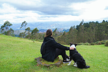 Back view of a young woman and her dog looking at the Picos de Europa in Asturias