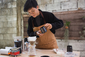 Asian people making coffee for dripping hot coffee into the cup with equipment, tool brewing on the table.