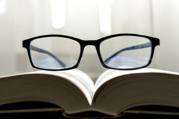 Close-up photo of eyeglasses on the book in education and reading book concept