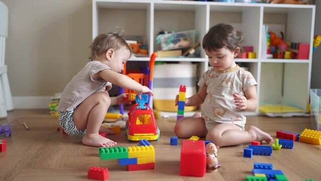 baby group children playing toys on the floor in kindergarten. happy family kid concept. baby twins brother sister play toys dream scattered on indoors. development of fine motor skills concept