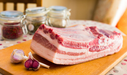 fresh piece of pork belly on wooden board with spices