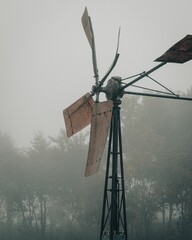 Closeup of an old rusty windmill against a foggy sky