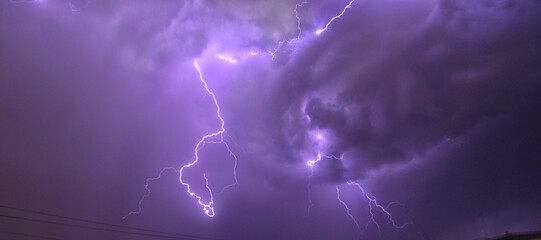Panoramic view of lightning illuminating the dark purple cloudy sky