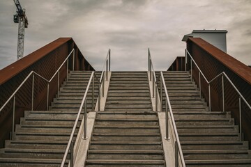 Stairway leading onto a bridge with wooden railings under a dark gray sky on a gloomy day