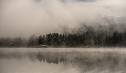 Beautiful view of the foggy Wasa Lake with trees in the background