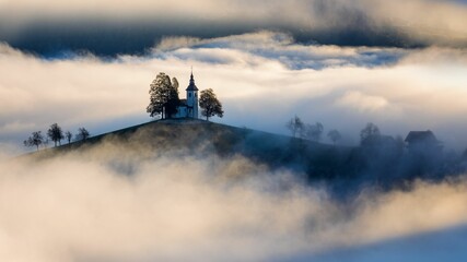 Dramatic shot of St. Thomas church in Slovenia in a foggy day