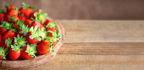 Strawberries in a plate on a wooden table copy space. Strawberries background. Top view. Healthy...