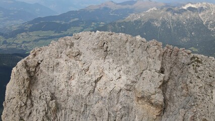 Aerial shot of a mountain top in the Alps of Italy with a valley in the background