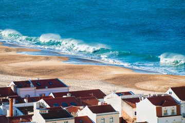 View of the sandy beach and ocean waves in Nazare, Portugal.
