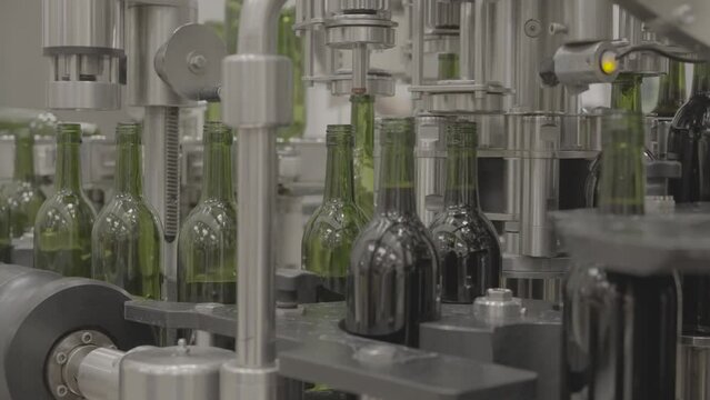 The wine bottling machine, cleaning bottles with CO2, filling bottles, and adding screw tops, in 4K