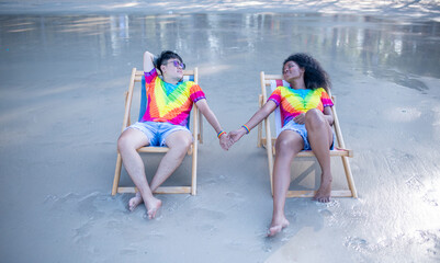Happiness couple LGBTQ lover sitting on beach chair holding hand show happiness with equality...