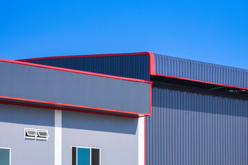 Industrial office building next to metal warehouse against blue clear sky background, side view...