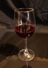 A glass of red wine on a black shiny background.