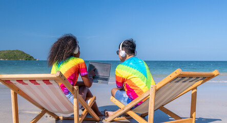 Happiness Lesbian LGBTQ couples sitting on chair beach listen to music together on the beach with headphone relaxed on summer holidays is equality freedom lover concept.
