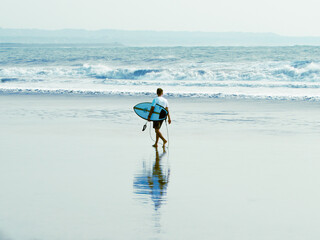 A Man Walking on the Beach with Surfboard © Nilufer