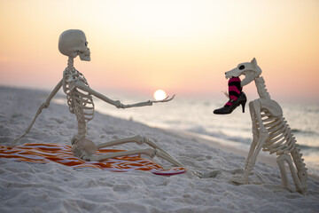 skeleton on the beach on Halloween holding the sun  at sunrise 