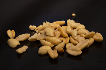 Salty peanut nuts lie on a black background.