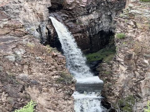 Vertical drone footage of a waterfall flowing down rocky hill