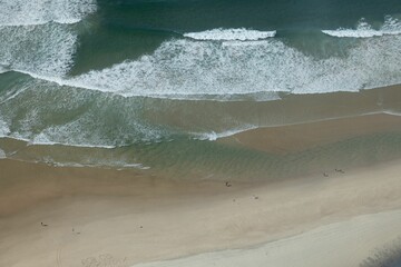 Aerial of sea tidal waves coming towards the shore on a sunny day
