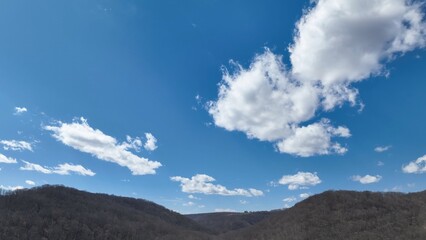 Blue sky with white clouds and mountain range landscape in winter and early springtime in Pennsylvania mountains