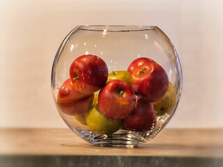 Closeup shot of red and yellow apples in the glass bowl