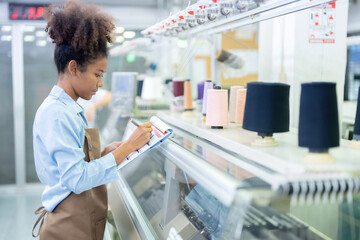 American female designer, seamstress taking customer orders, standing near weaving machines and...