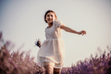 Lavender field happy girl in white dress with a scythe runs through a lilac field of lavender....