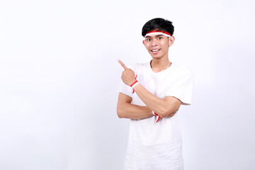 Happy asian young boy with red white ribbon celebrating Indonesia independence day while pointing...