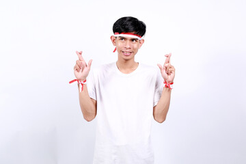 Young asian boy with red white ribbon celebrating Indonesia independence day while making cross...
