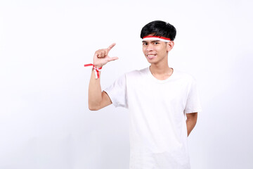 Young asian boy with red white ribbon celebrating Indonesia independence day while holding...