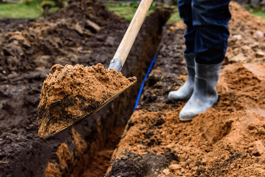 Earthworks, man digging trench using shovel.