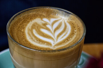 Close-up of fresh cappuccino with froth art served in mug on table at cafe.