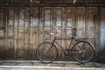 Vintage bicycle on old rustic dirty wall house, many text on wood wall. Classic bike old bicycle on...