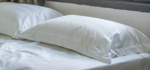 Soft pillows and white towel on clean white bed. Pillows bed with bedding sheets in bedroom. Bed...